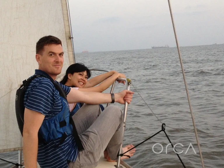 A couple at the helm of a J24 sailing yacht in Mumbai harbour