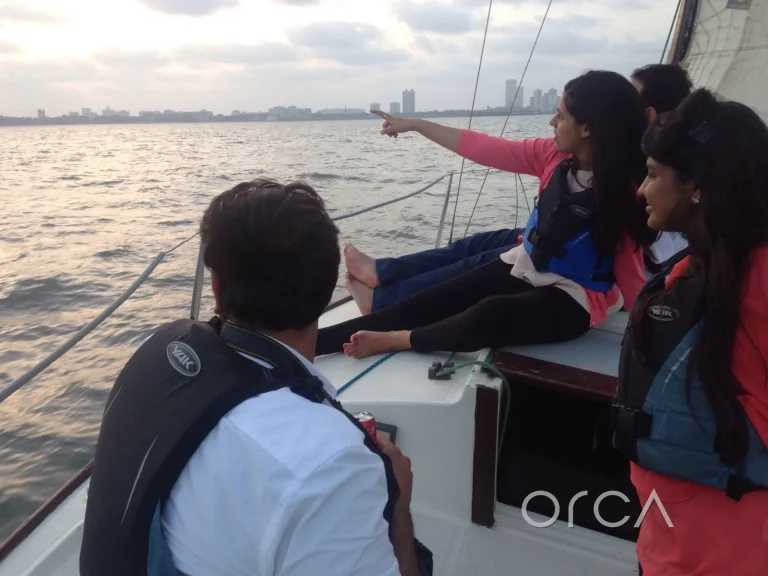 Guests looking out at the Mumbai skyline from a J24 under sail