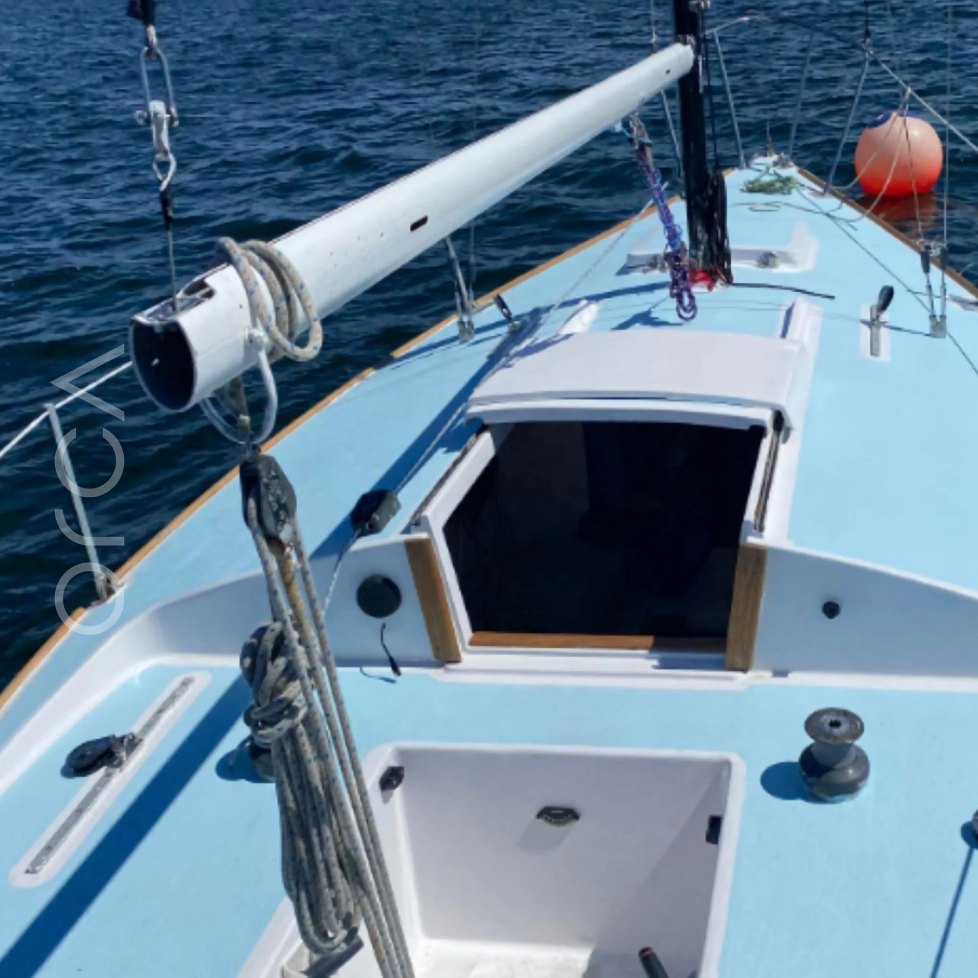 The foredeck of a J24 sailboat in Mumbai, looking forward past the hatch to the bow, available to rent from Orca Sail.