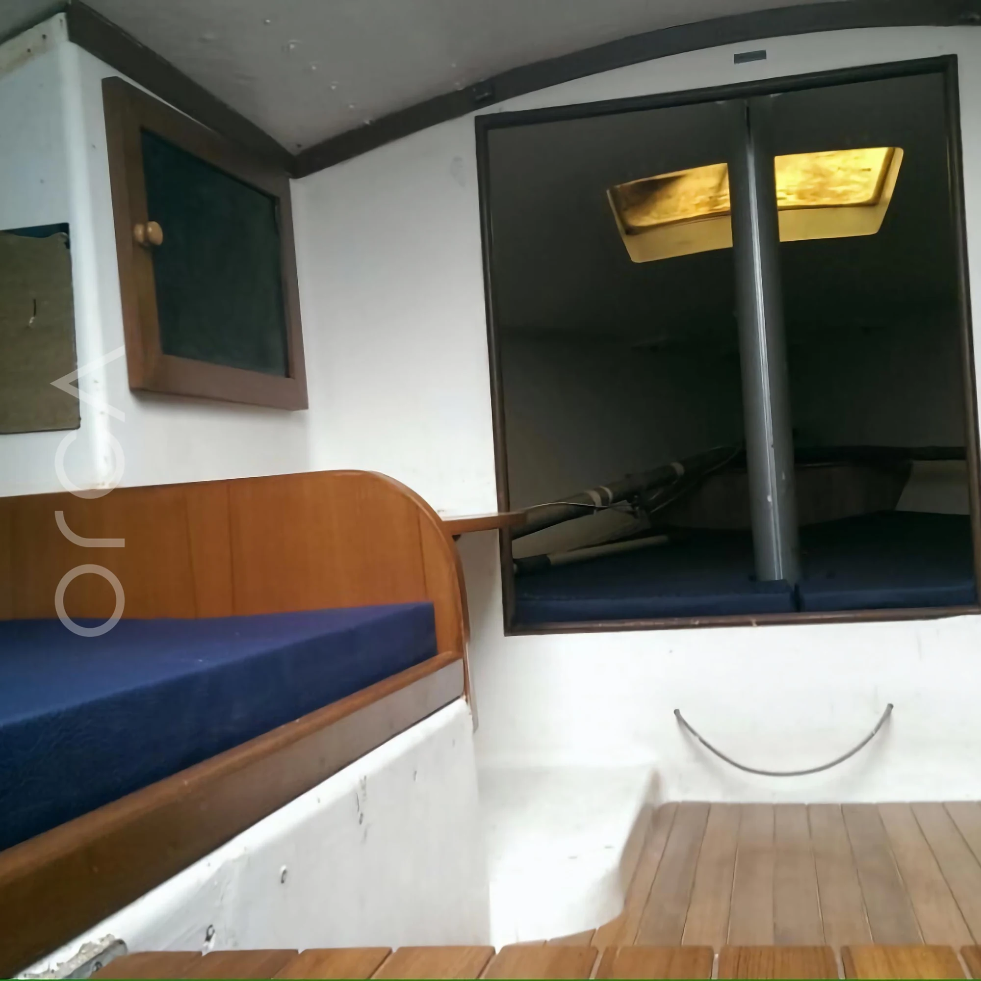 The small cabin below deck on a J24 sailboat in Mumbai, with cushioned berths on either side, available to rent from Orca Sail.