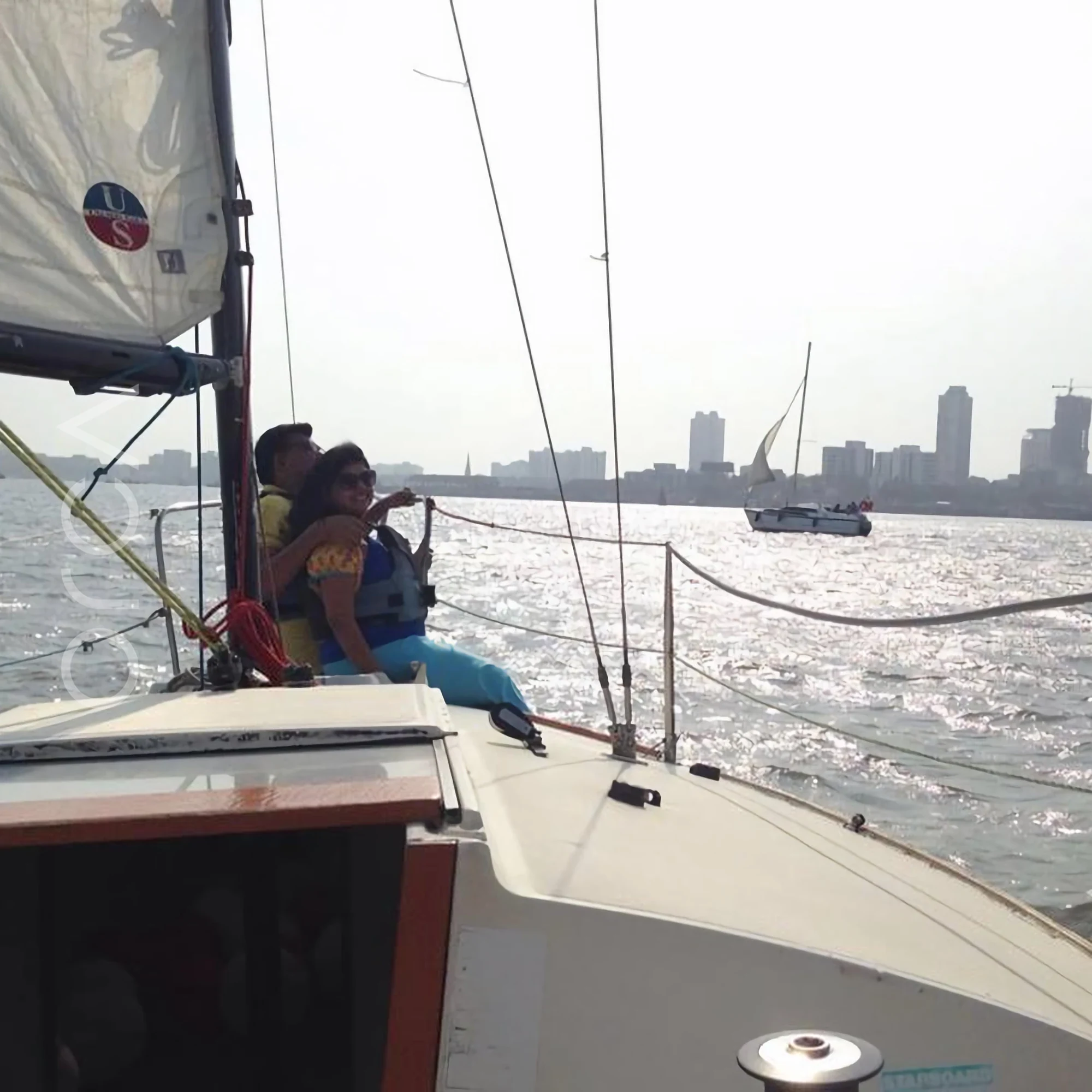 Guests in life jackets in the cockpit of a J24 sailboat in Mumbai harbour, available to rent from Orca Sail.