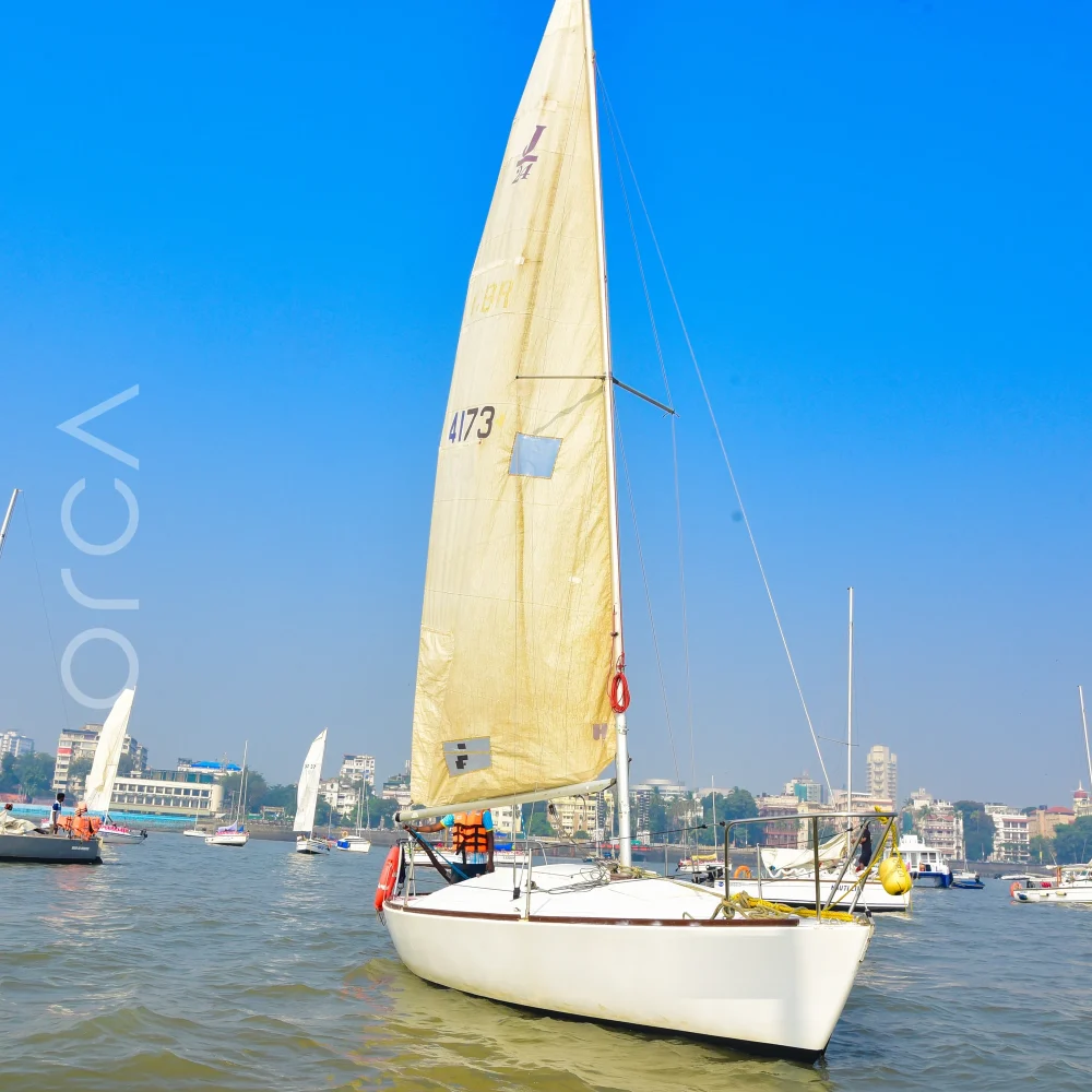 A J24 sailboat under sail in Mumbai harbour, available to rent from Orca Sail.