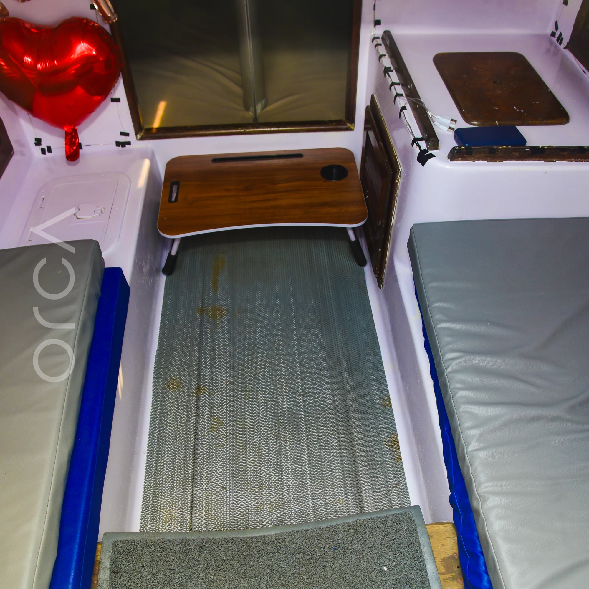 The cabin of a J24 sailboat in Mumbai, with cushioned berths on each side.