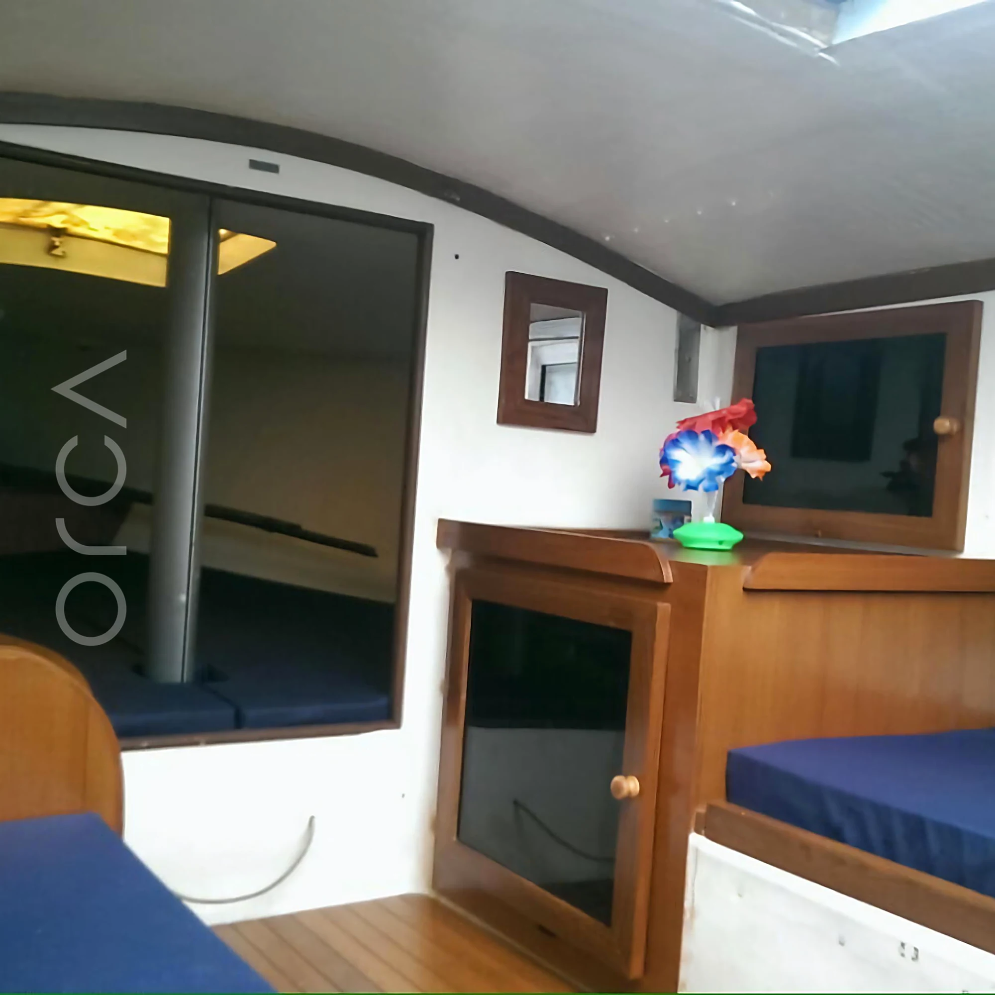 The small cabin below deck on a J24 sailboat in Mumbai, with cushioned berths on either side, available to rent from Orca Sail.