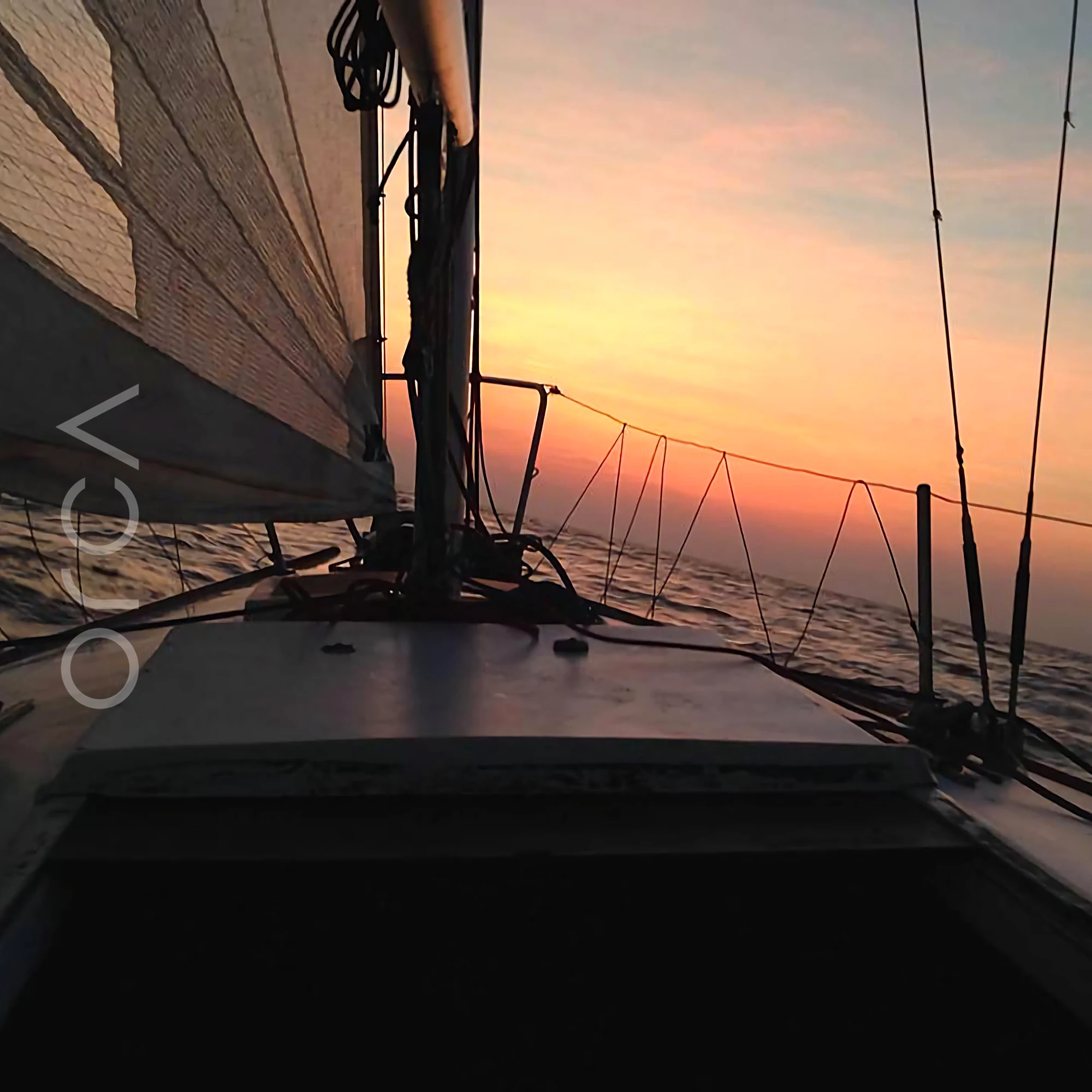 Sunset over the bow from the cockpit of a J24 sailboat in Mumbai, available to rent from Orca Sail.