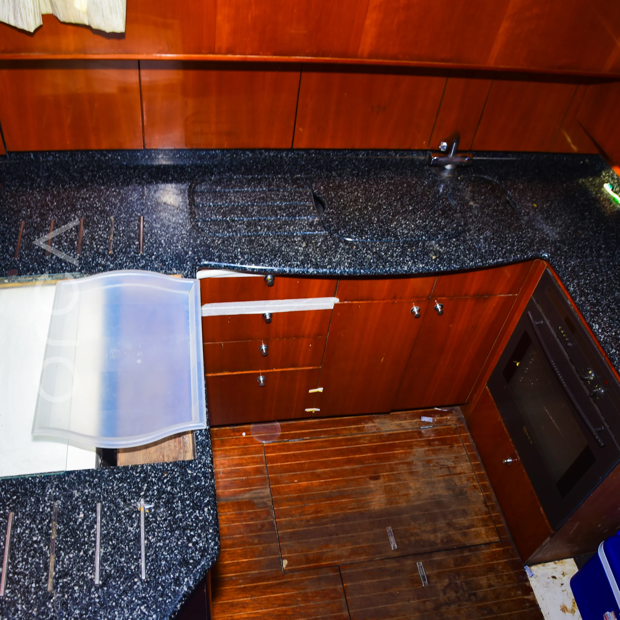 The galley of a Princess 61 motor yacht in Mumbai, with a granite counter and storage, available to rent from Orca Sail.