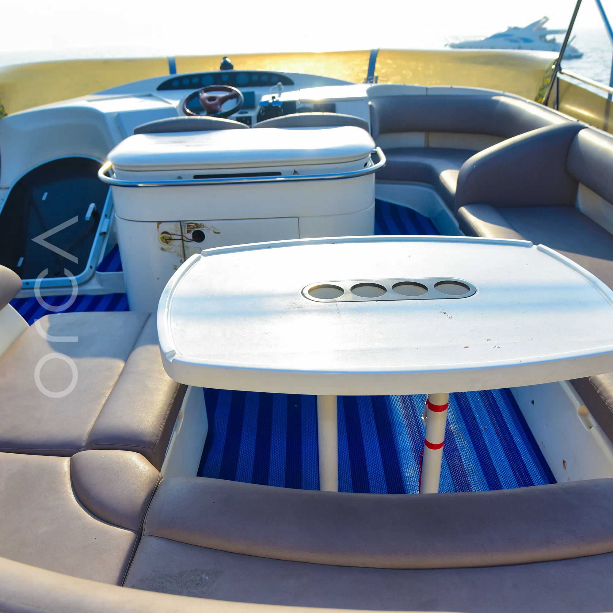 The flybridge of a Princess 61 motor yacht in Mumbai, with the helm, wraparound seating and a table, available to rent from Orca Sail.