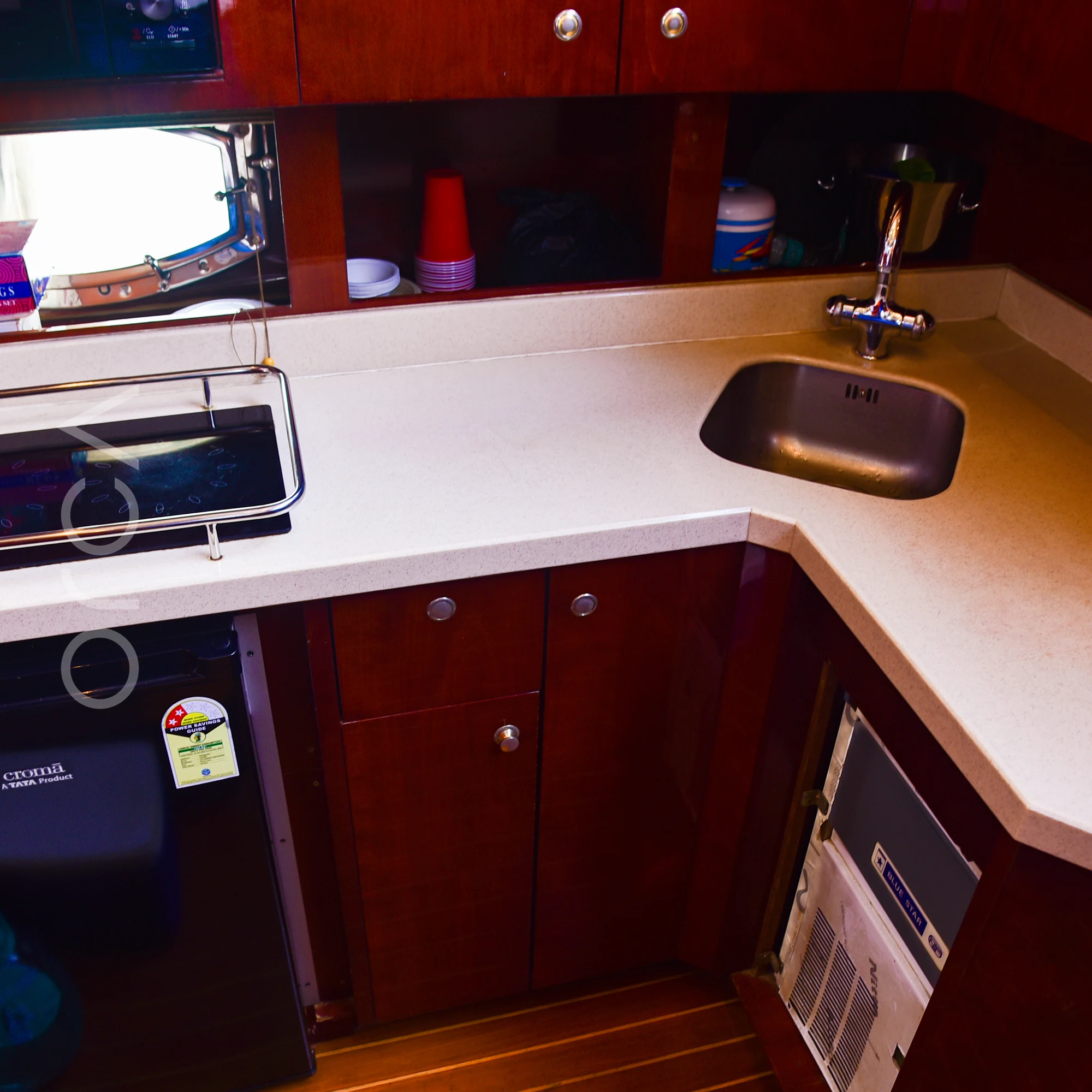 The galley of a Majesty 44 motor yacht in Mumbai, with a hob, a sink, a fridge and counter space, available to rent from Orca Sail.