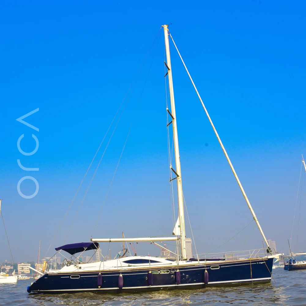 The Jeanneau 54 sail yacht seen side-on at anchor in Mumbai harbour, mast and rigging in full, available to rent from Orca Sail.