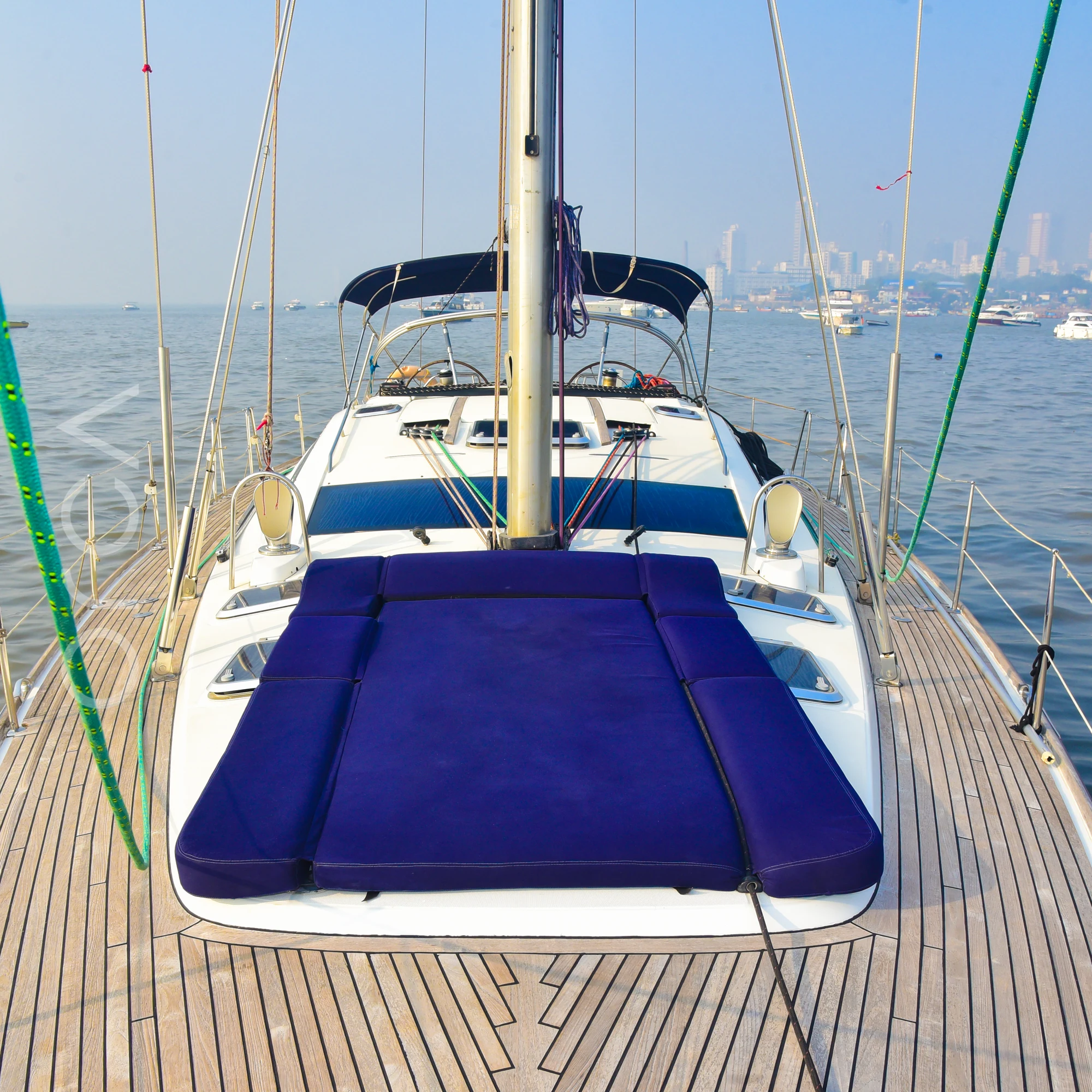 The foredeck sunpad of a Jeanneau 54 sail yacht in Mumbai, looking aft to the cockpit, available to rent from Orca Sail.