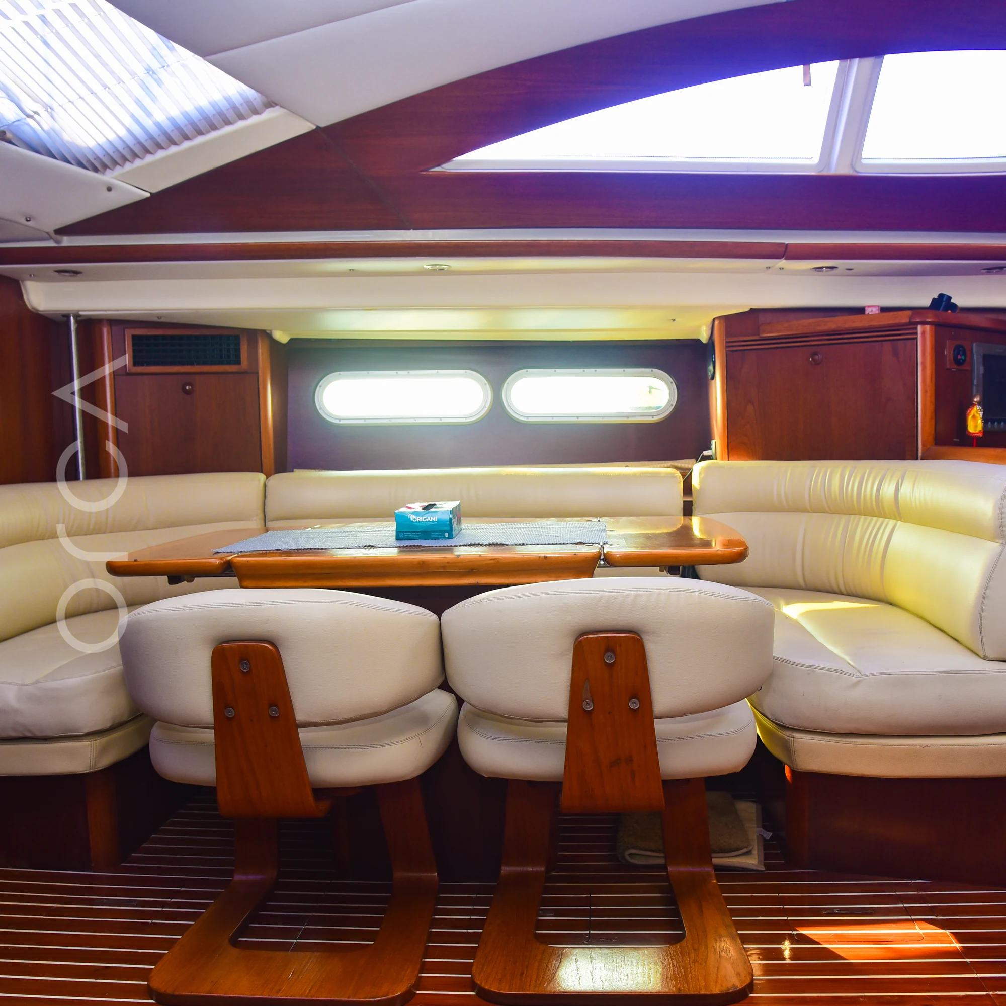 The dining area of a Jeanneau 54 sail yacht in Mumbai, with a table, two chairs and sofa seating, available to rent from Orca Sail.