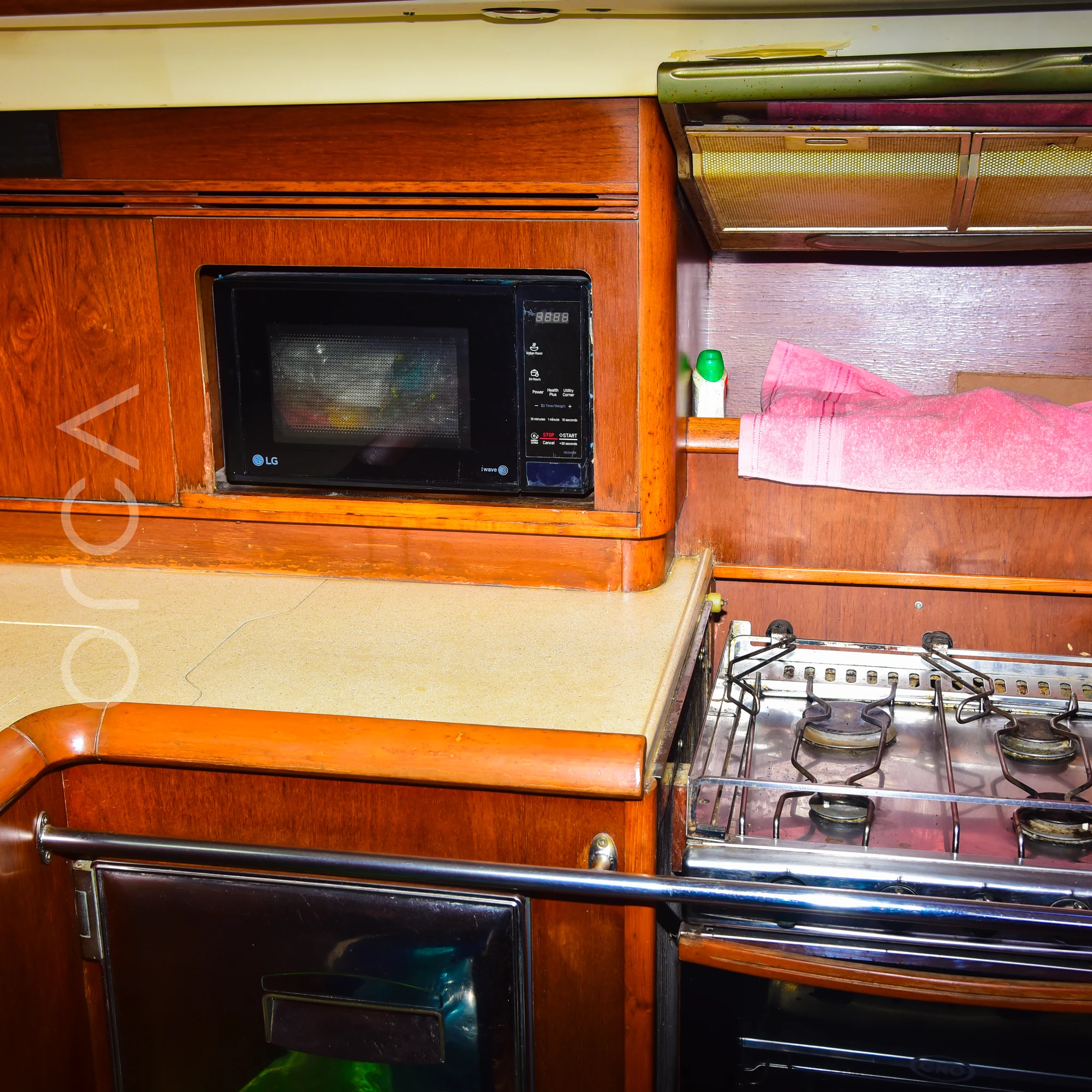 The galley of a Jeanneau 54 sail yacht in Mumbai, with a gas hob and oven, a microwave and counter space, available to rent from Orca Sail.