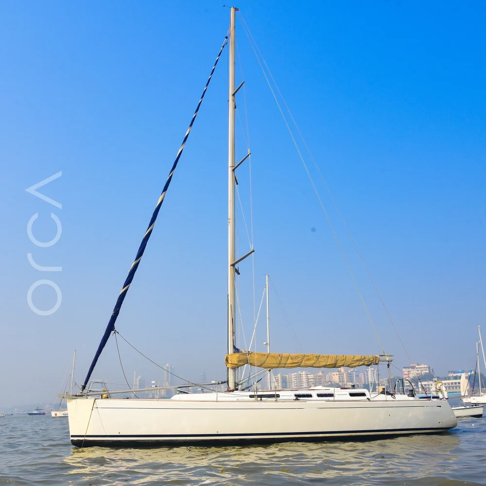 The Grand Soleil 45 sail yacht seen side-on at anchor in Mumbai harbour, mast and rigging in full, available to rent from Orca Sail.
