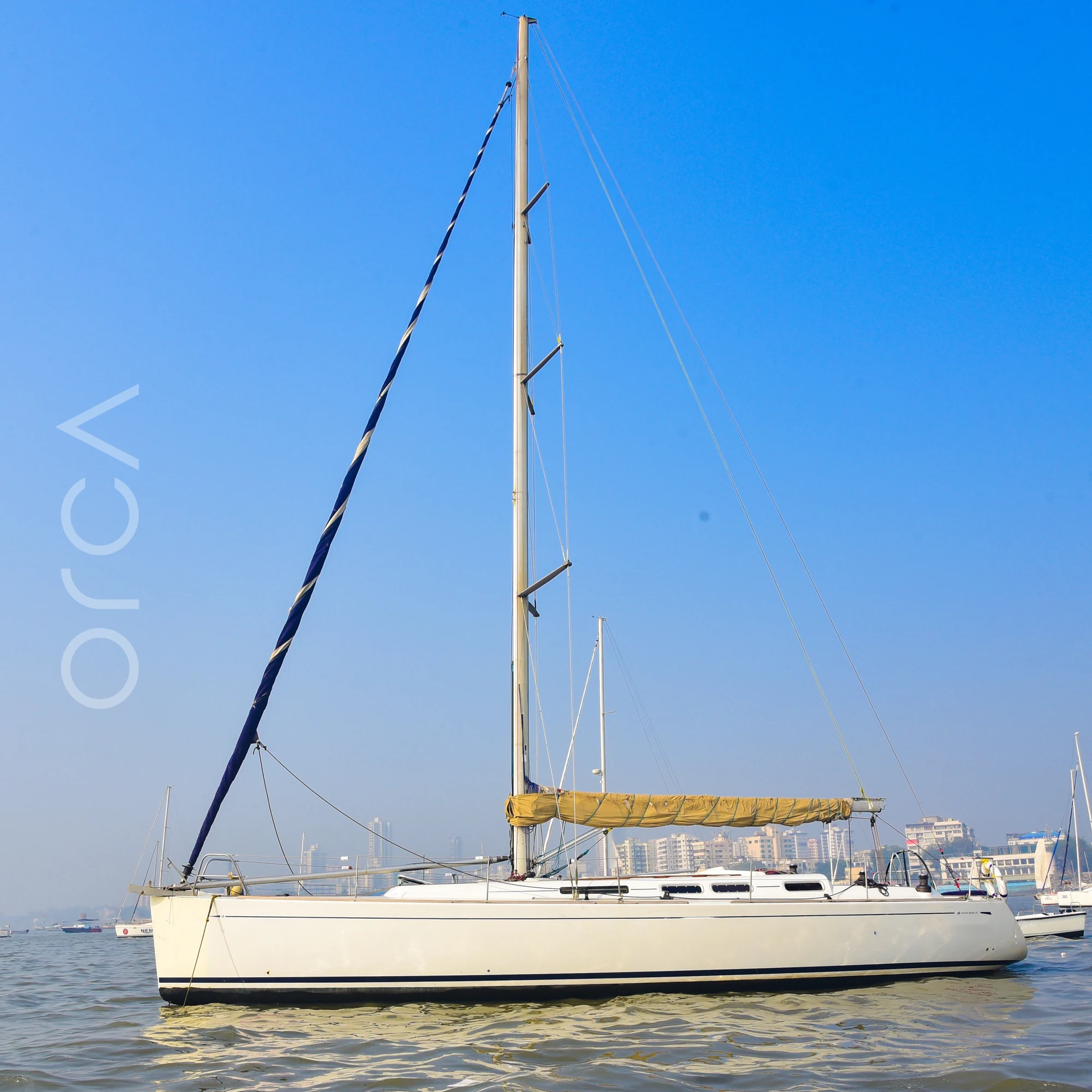 The Grand Soleil 45 sail yacht seen side-on at anchor in Mumbai harbour, mast and rigging in full, available to rent from Orca Sail.