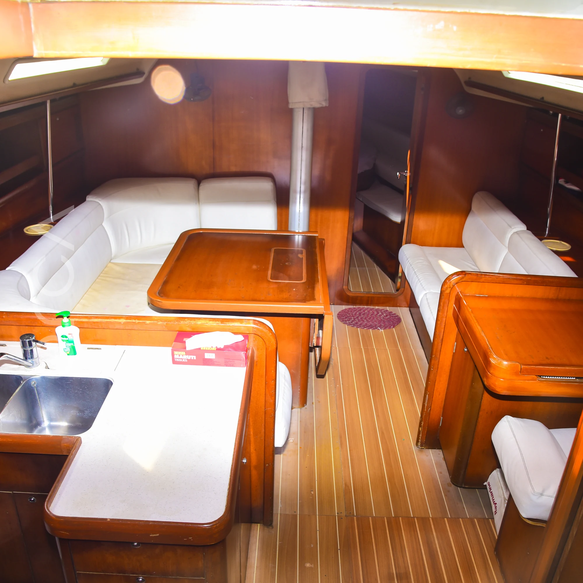 The main salon of a Grand Soleil 45 sail yacht in Mumbai, with sofa seating, a table and the galley counter, available to rent from Orca Sail.
