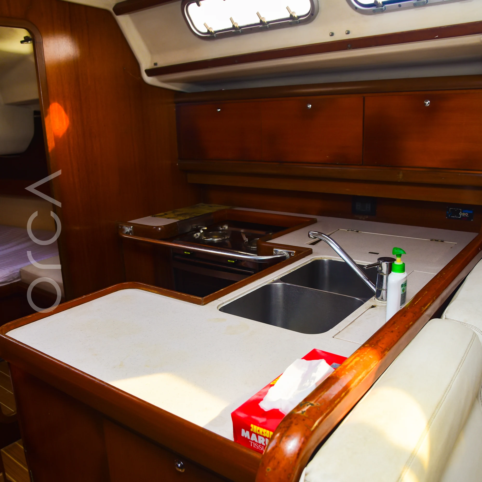 The galley of a Grand Soleil 45 sail yacht in Mumbai, with a gas hob, a double sink and counter space, available to rent from Orca Sail.